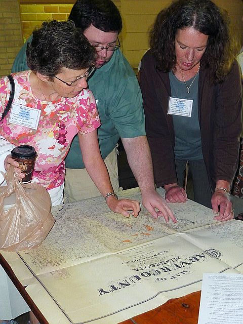 Mom Margaret Pauley Oman, son Andy Oman, and Rae Stimler Bordua locating the family homesteads on Carver County plat map provided by Bob Mullally, photograph courtesy of Don Jurek
