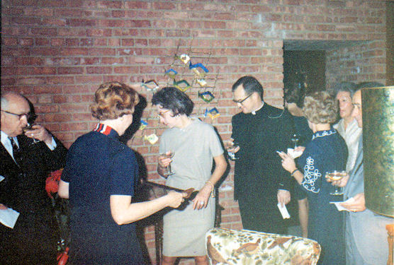 Joyce Bussell serving champagne, and Father Garvey drinking booze to Queenie's left