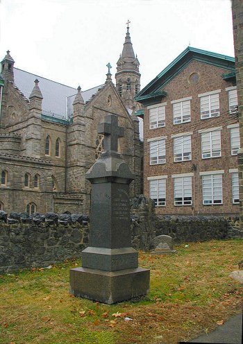 Gravestone with St. John the Baptist Church and school in background