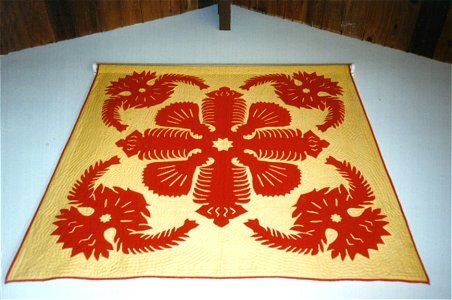 Dramatic traditional Hawaiian quilt with large floral motif.