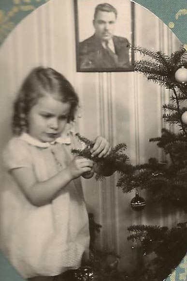 Nancy Carolyn Johnson decorating a Christmas tree with a picture of her father Dewey in the background